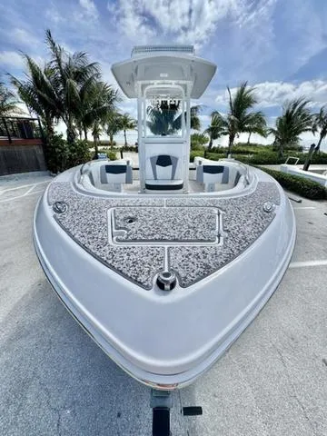 Slide: The Image of 2023 Robalo R230 boat, front view, parked with palm trees and cloudy sky background. - 21
