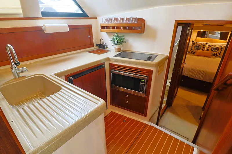 Slide: The Image of 2000 Riviera Flybridge Convertible yacht kitchen with modern amenities and cozy bedroom. - 14