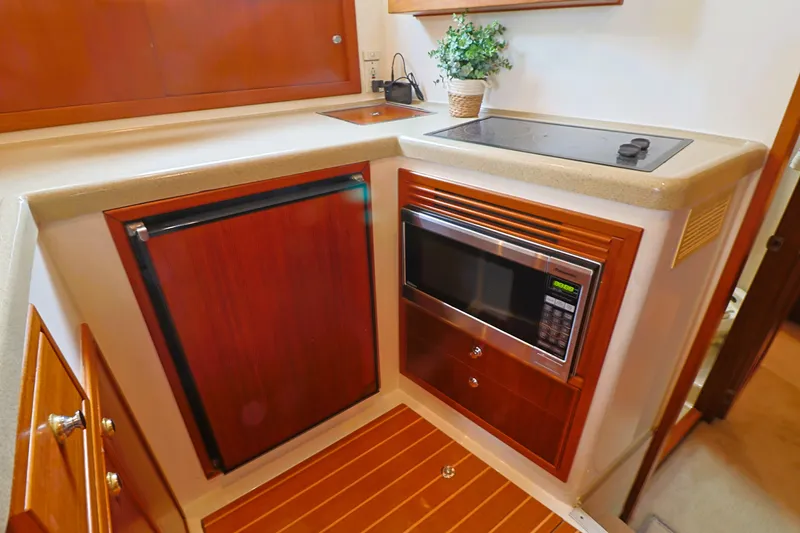 Slide: The Image of Compact kitchen area in a 2000 Riviera Flybridge Convertible yacht with microwave and mini fridge. - 15