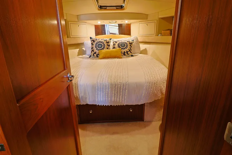 Slide: The Image of Cozy bedroom in 2000 Riviera Flybridge Convertible yacht with elegant bedding and wooden accents. - 17