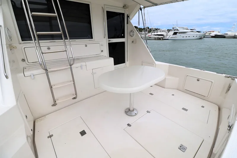 Slide: The Image of 2000 Riviera Flybridge Convertible yacht deck with table and ladder, docked at marina. - 25