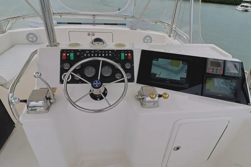 Slide: The Image of Control panel of a 2000 Riviera Flybridge Convertible yacht with steering wheel and navigation screens. - 27