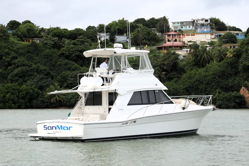 Slide: The Image of 2000 Riviera Flybridge Convertible yacht on water, lush green background. - 4