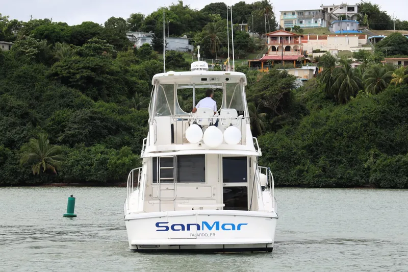 Slide: The Image of Riviera Flybridge Convertible 2000 boat on water, lush green hillside background. - 5