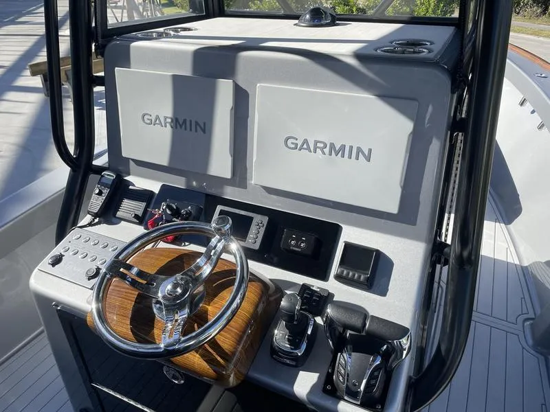 Slide: The Image of 2020 Stuart 27 CC boat dashboard with Garmin displays and wooden steering wheel. - 16