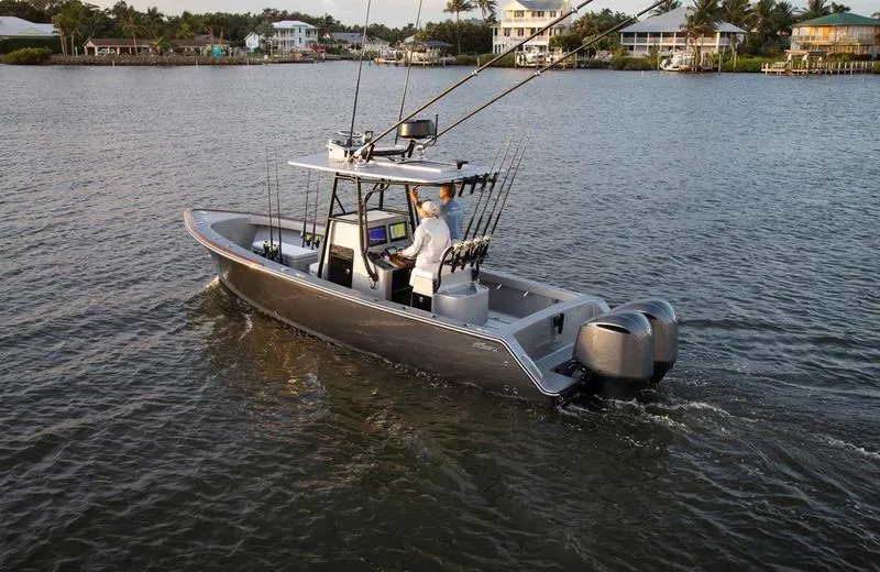 Slide: The Image of 2020 Stuart 27 CC boat cruising on a calm waterway, equipped for fishing. - 4