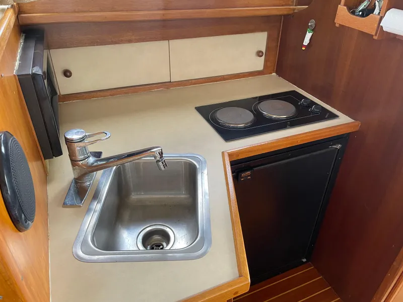 Slide: The Image of 1967 Hatteras 28 Cruiser kitchen with sink, stove, and compact fridge. - 12