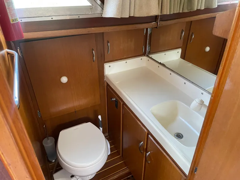 Slide: The Image of 1967 Hatteras 28 Cruiser bathroom with wooden cabinets, sink, and toilet. - 15