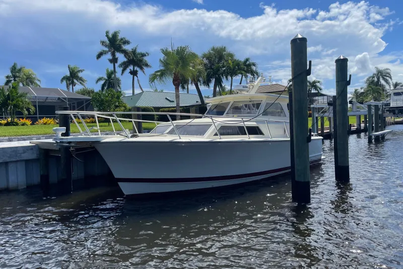 Slide: The Image of 1967 Hatteras 28 Cruiser docked by palm trees under a blue sky. - 3