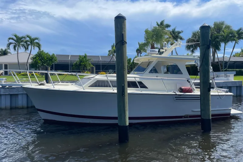Slide: The Image of 1967 Hatteras 28 Cruiser docked by waterfront with palm trees and clear sky. - 1