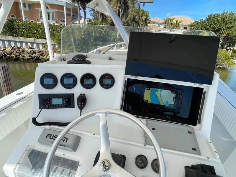 Slide: The Image of 2001 Jupiter 31 Cuddy boat helm with navigation instruments and steering wheel, docked by waterfront homes. - 3