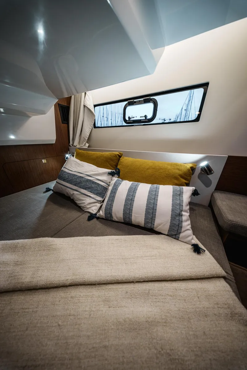 Slide: The Image of 2025 Beneteau Antares 9 cabin interior with cozy bedding and window view. - 15
