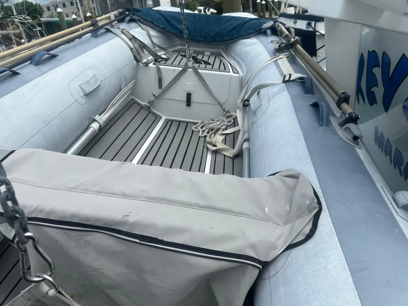 Slide: The Image of 1999 Mainship 430 Trawler with inflatable dinghy on deck, featuring wooden flooring and protective cover. - 17
