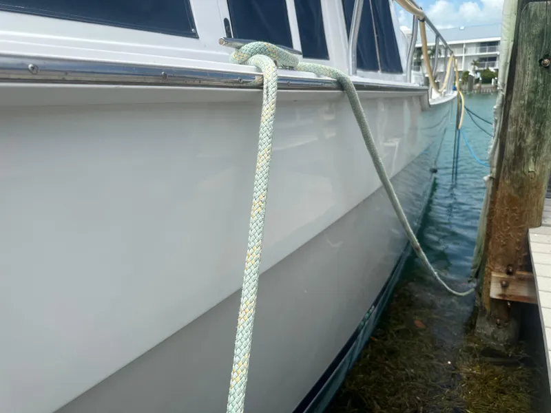 Slide: The Image of 1999 Mainship 430 Trawler docked, secured with rope, side view. - 24
