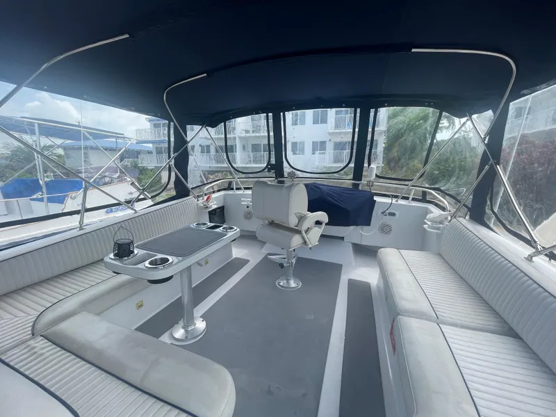Slide: The Image of 1999 Mainship 430 Trawler interior with seating, table, and helm station under canopy. - 30