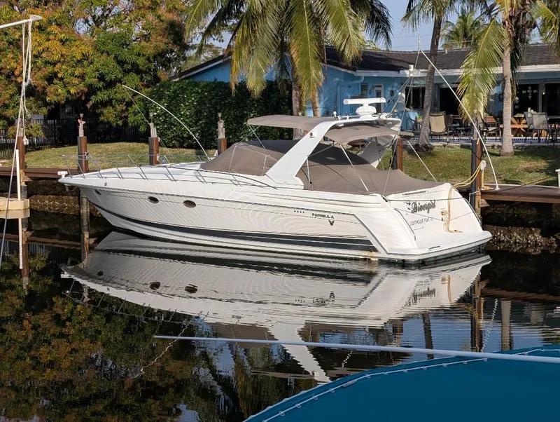 Slide: The Image of 2002 Formula 41 PC yacht docked by palm trees, reflecting on calm water. - 2