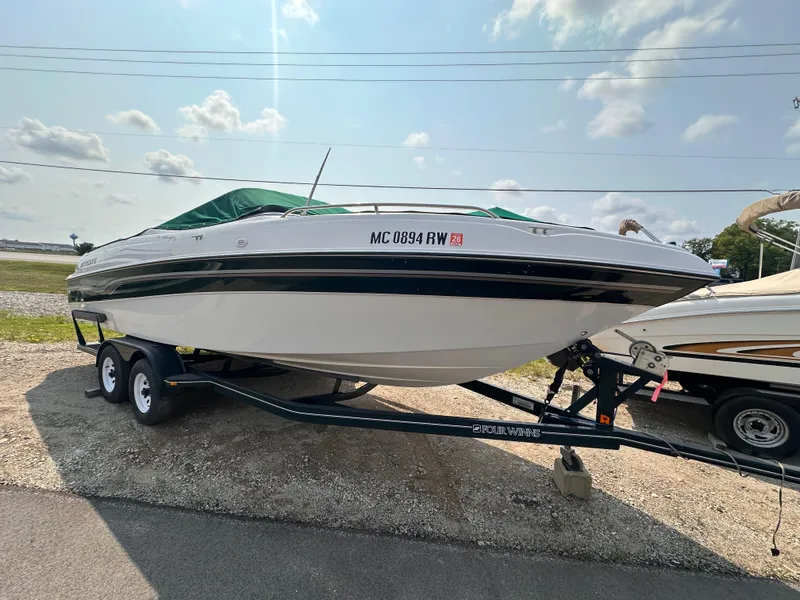 Slide: The Image of 1999 Four Winns 240 Horizon boat on trailer, parked outdoors under a partly cloudy sky. - 0