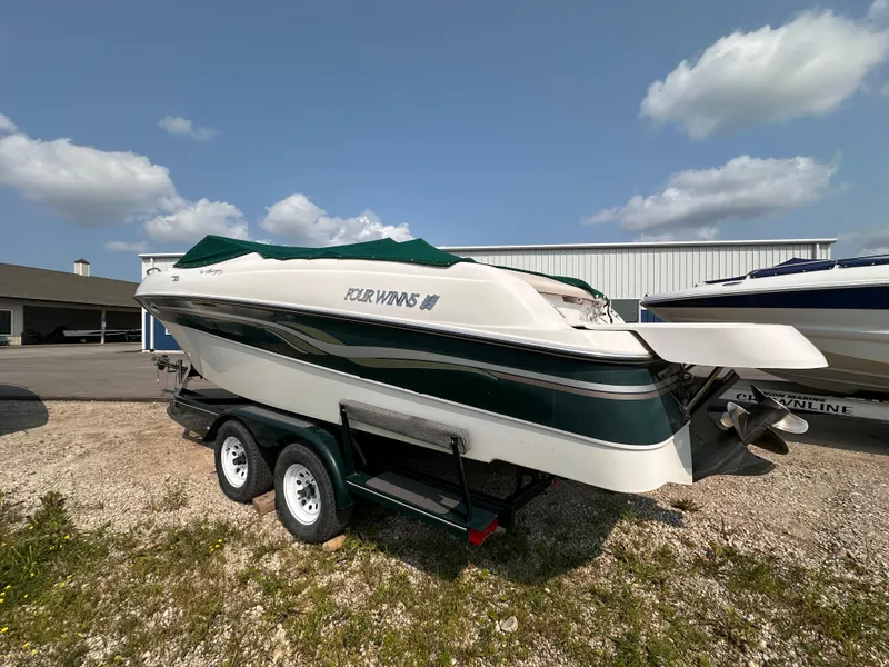 Slide: The Image of 1999 Four Winns 240 Horizon boat on trailer, parked outdoors under a clear sky. - 2
