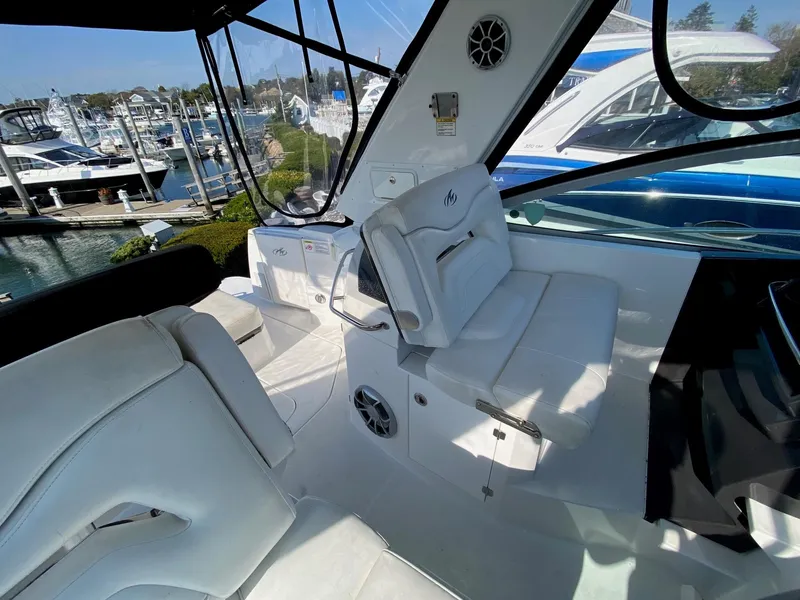 Slide: The Image of Interior of a 2015 Monterey 335 Sport Yacht with white seating and marina view. - 12