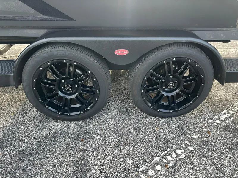 Slide: The Image of Black alloy wheels on a 2024 iKon LX21 trailer, parked on asphalt. - 8