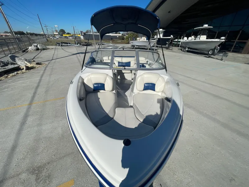 Slide: The Image of 2012 Tahoe Q4 SS boat with open bow seating, parked outdoors. - 2