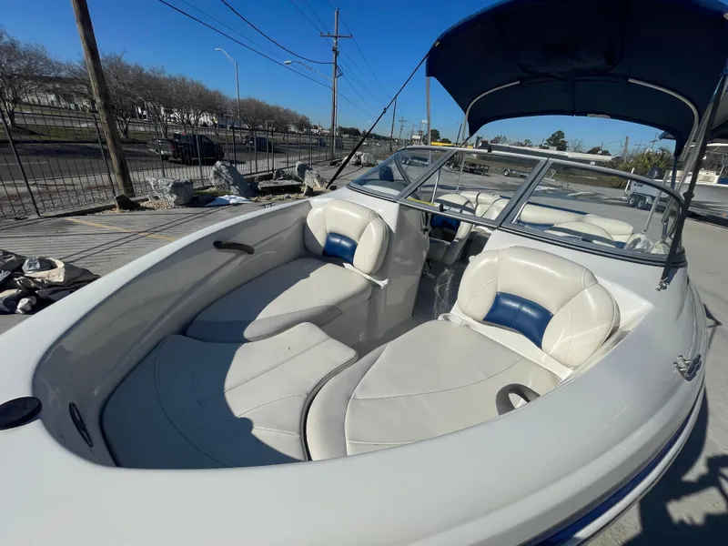Slide: The Image of 2012 Tahoe Q4 SS boat with white and blue interior, docked under clear blue sky. - 9