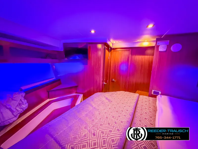 Slide: The Image of 2021 Four Winns Vista 355 Coupe OB cabin with ambient blue lighting and cozy bedding. - 23