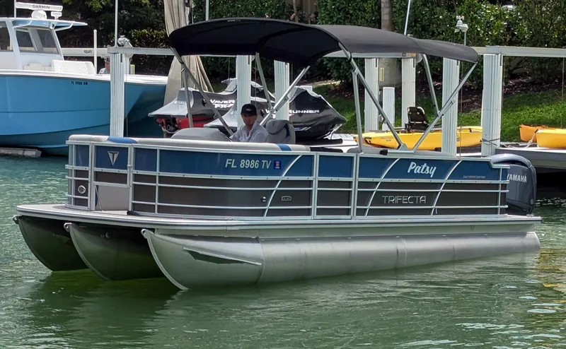 Slide: The Image of 2024 Trifecta 22TRFC LE 2.75 pontoon boat docked in a marina. - 0