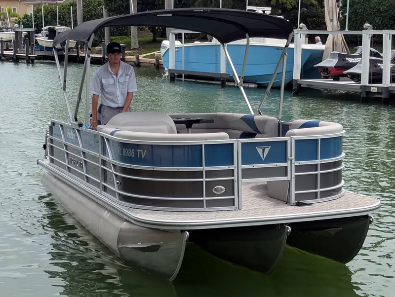 Slide: The Image of 2024 Trifecta 22TRFC LE 2.75 pontoon boat on water, featuring a canopy and modern design. - 2