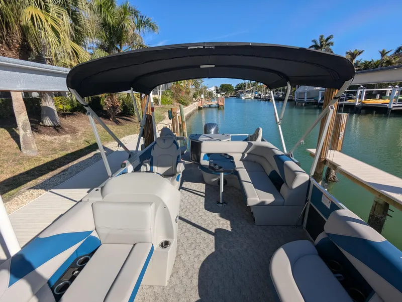 Slide: The Image of 2024 Trifecta 22TRFC LE 2.75 pontoon boat docked by a scenic canal. - 22