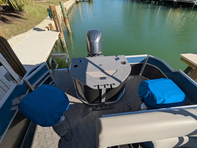 Slide: The Image of 2024 Trifecta 22TRFC LE 2.75 pontoon boat with blue-covered seats at a dock. - 29