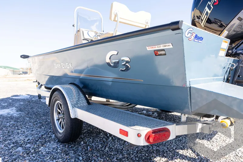 Slide: The Image of 2025 G3 Bay 21 GX boat on trailer, parked on gravel. - 22