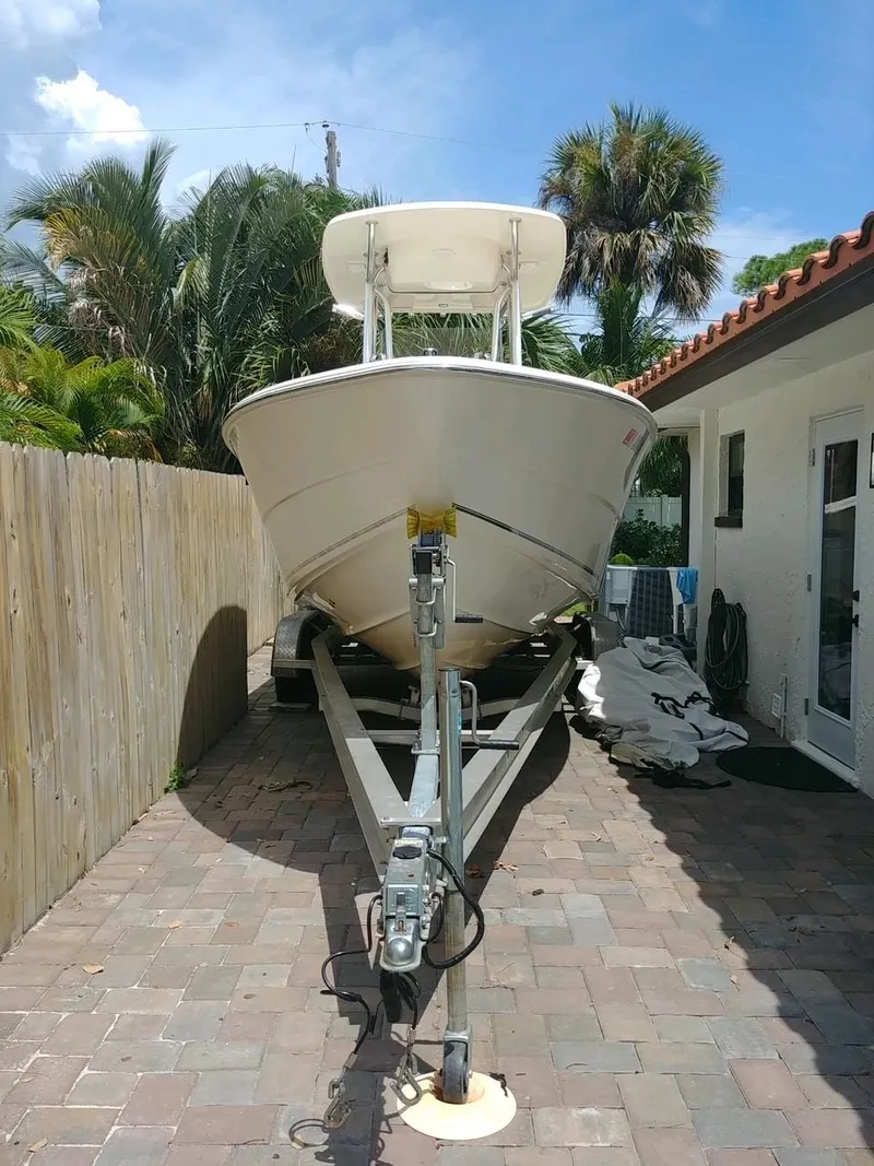 Slide: The Image of 2020 Bulls Bay 230 CC boat on trailer, parked beside a house with palm trees. - 10