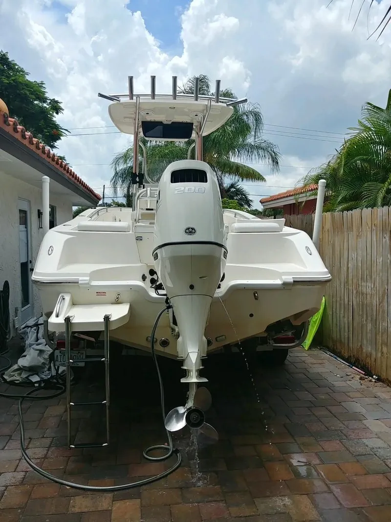 Slide: The Image of 2020 Bulls Bay 230 CC boat parked on a brick driveway, surrounded by tropical foliage. - 13