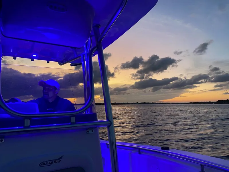 Slide: The Image of 2020 Bulls Bay 230 CC boat at sunset with blue interior lighting. - 3