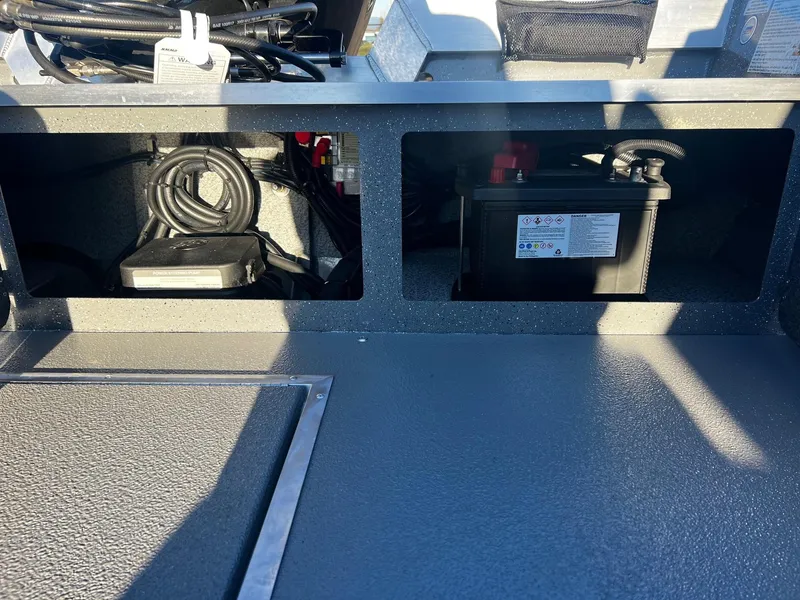 Slide: The Image of Storage compartments in a 2025 Thunder Jet 209 Rush OT boat, featuring cables and a battery. - 13