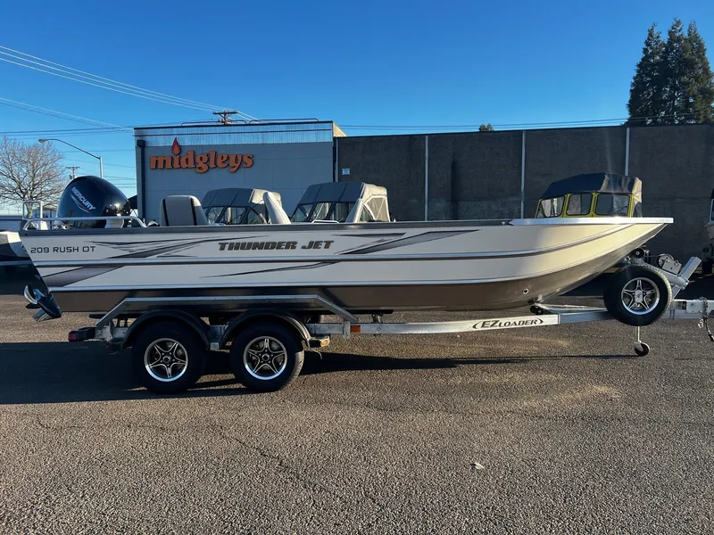 Slide: The Image of 2025 Thunder Jet 209 Rush OT boat on trailer, parked outdoors. - 2