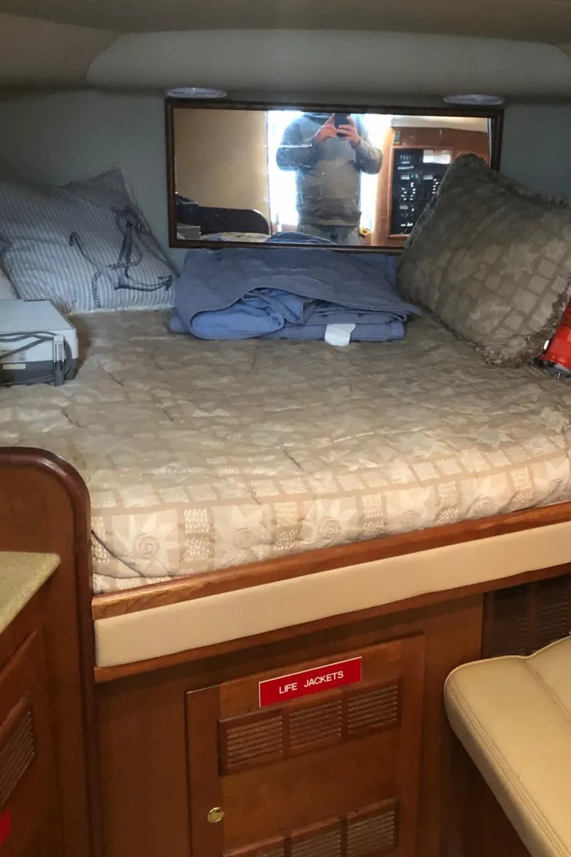 Slide: The Image of 2000 Rampage 30 Express cabin with bed, pillows, and life jackets storage. - 11