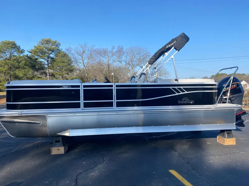 Slide: The Image of 2025 SunCatcher Select 322RC pontoon boat on blocks, black and silver design, outdoor setting. - 0