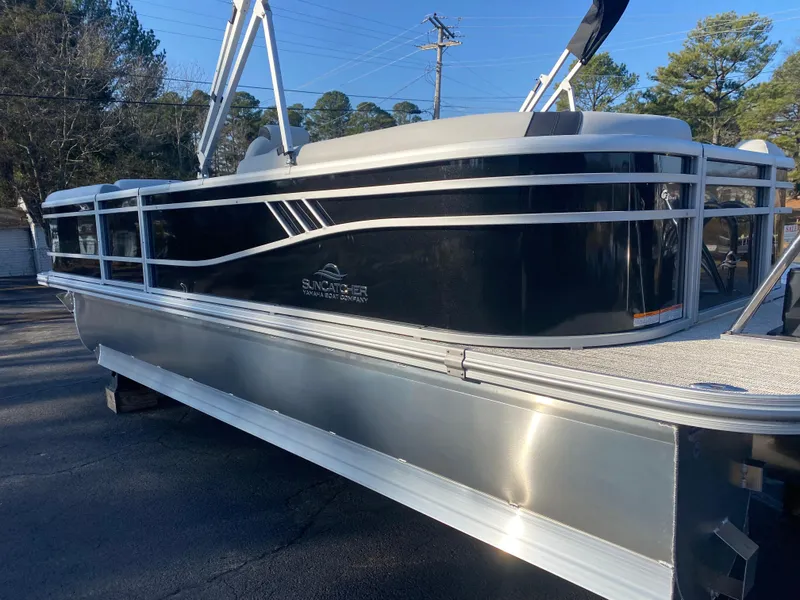 Slide: The Image of 2025 SunCatcher Select 322RC pontoon boat, sleek black design, parked outdoors. - 5