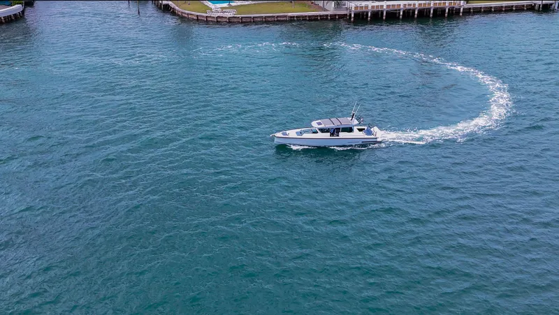 Slide: The Image of 2023 Axopar 37 XC CROSS CABIN cruising in clear blue waters near a dock. - 12