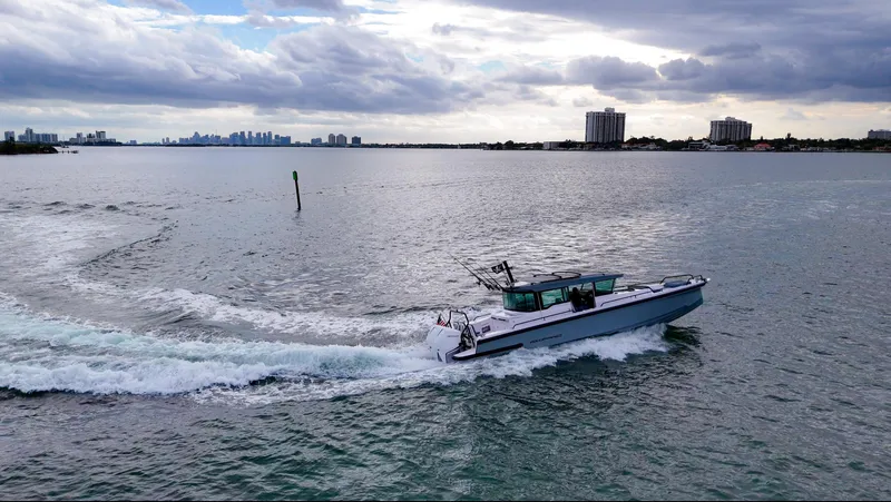 Slide: The Image of 2023 Axopar 37 XC CROSS CABIN cruising on a calm, scenic waterway. - 2
