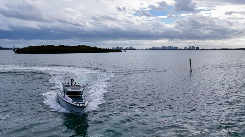 Slide: The Image of Axopar 37 XC CROSS CABIN 2023 cruising on open water with city skyline in background. - 3