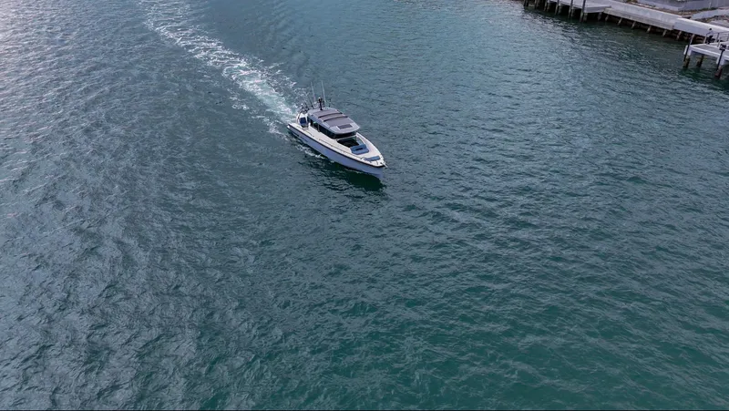 Slide: The Image of 2023 Axopar 37 XC CROSS CABIN cruising on open water near a dock. - 7