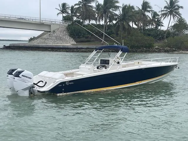 Slide: The Image of 2006 Marlago FS 35 Cuddy boat on water, with palm trees and bridge in background. - 2