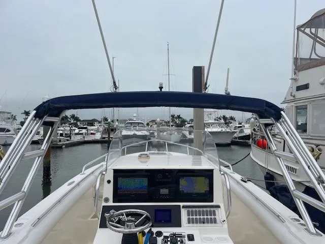 Slide: The Image of 2006 Marlago FS 35 Cuddy boat docked at marina, featuring navigation equipment and steering wheel. - 7
