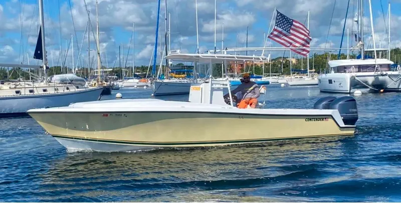 The Image of 2001 Contender 27' cuddy boat cruising in a marina, American flag waving. - 0
