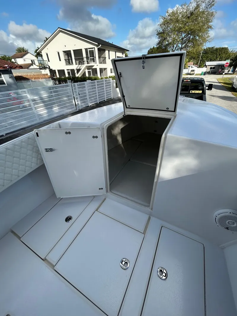 Slide: The Image of 2001 Contender 27' cuddy boat with open storage compartments, docked outdoors. - 12