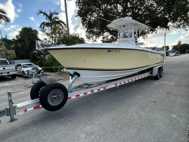 Slide: The Image of 2001 Contender 27' cuddy boat on trailer, parked on a street with trees in the background. - 3