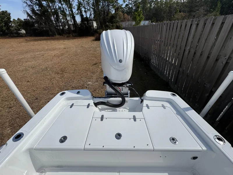 Slide: The Image of 2025 BlackJack 224 boat with outboard motor, parked on grass near a wooden fence. - 13